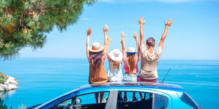 Family road trip with kids on blue car by ocean