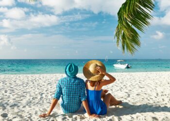 Luxury Island Hopping: Romantic couple sitting on white sand beach