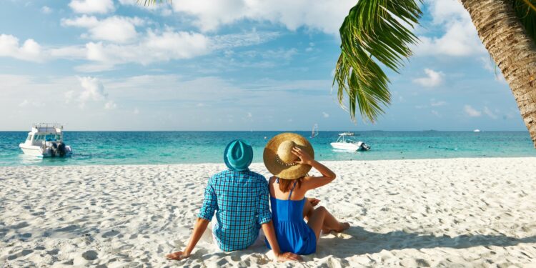 Luxury Island Hopping: Romantic couple sitting on white sand beach