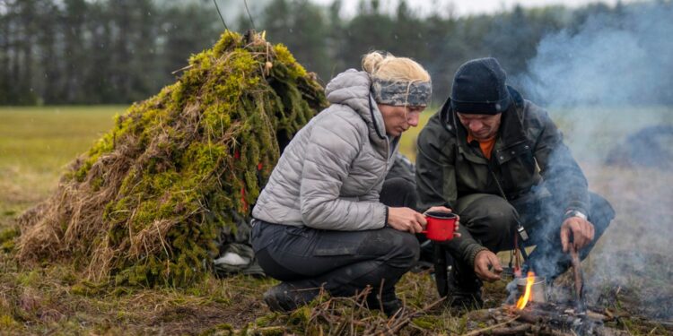 Wilderness survival: Hiker couple brewing tea over open fire
