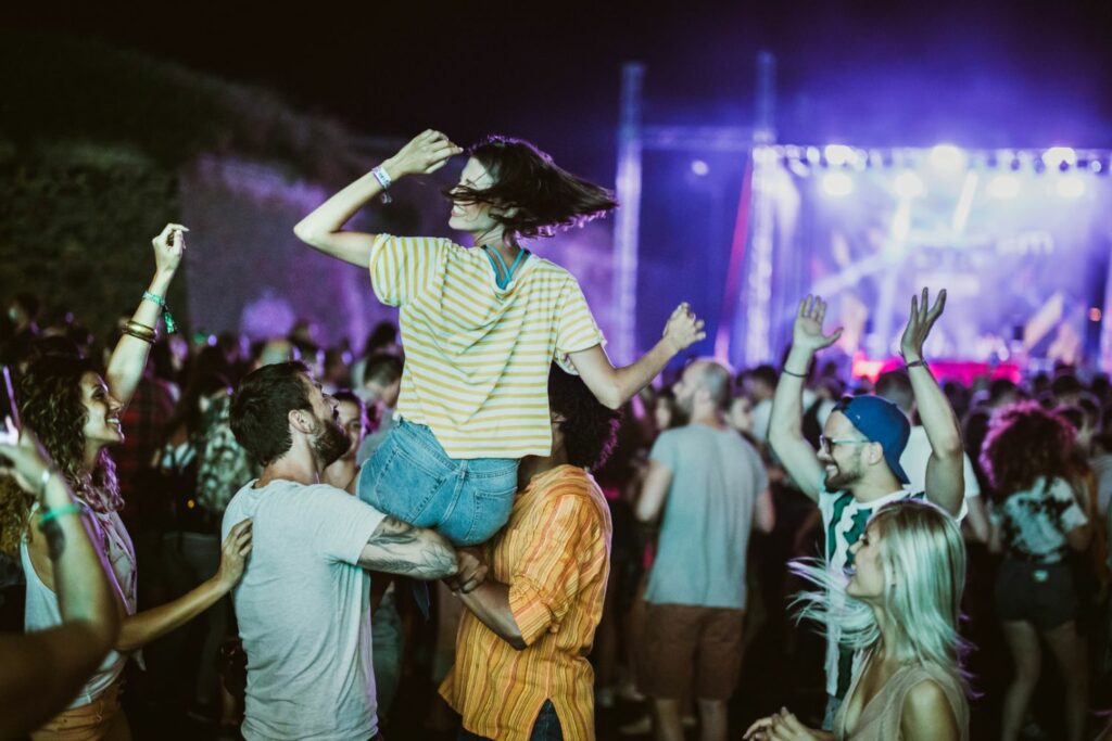 Two Men Carrying a Woman While Dancing at One of The Best Music Festivals (Source: Canva)