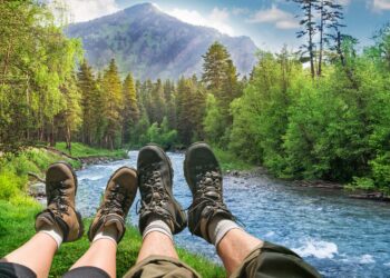 A couple's view of the mountain, green trees, river, tent, while hiking and camping (Source: Canva)