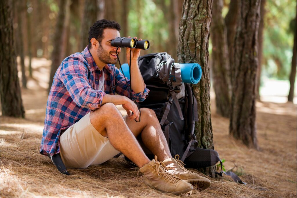 A Male Backpacker Using Binoculars in Exploring Nature (Source: Canva)