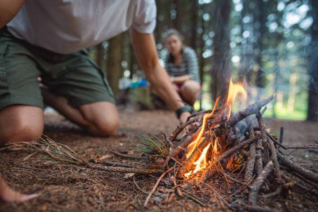 Making bonfire with small tree branches on hiking and camping trip (Source: Canva)