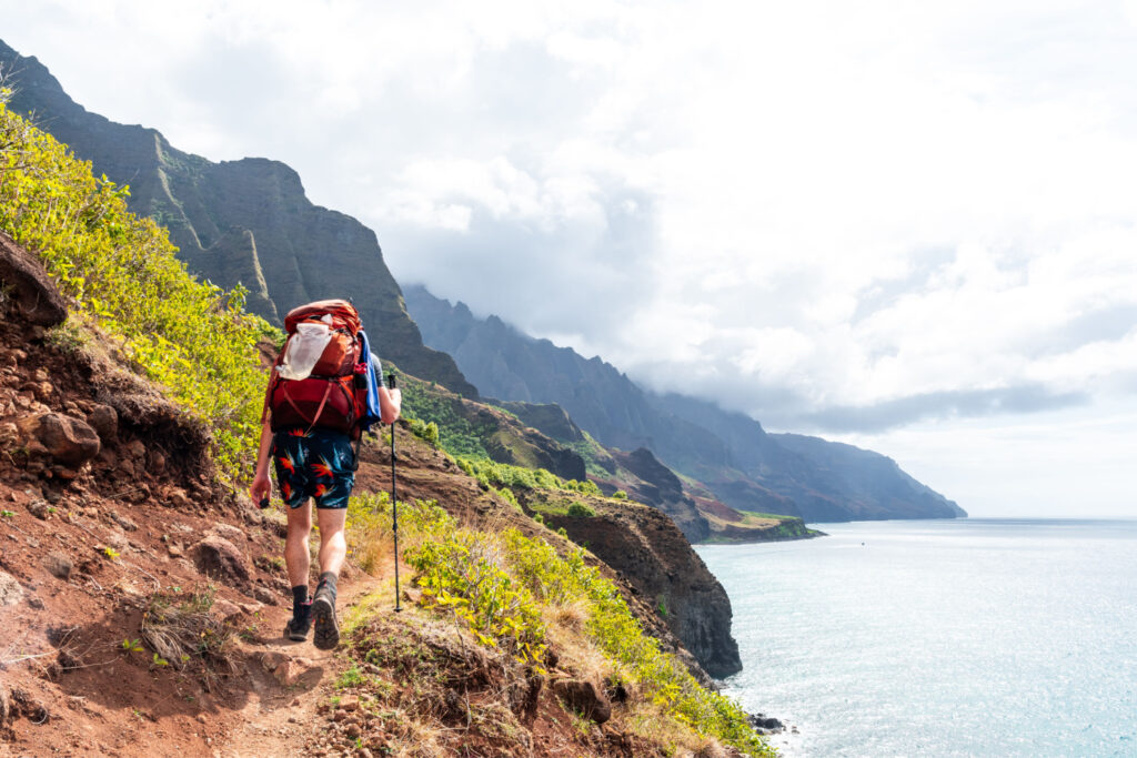 Hiker on a treacherous coastal Kalalau Trail, Hawaii