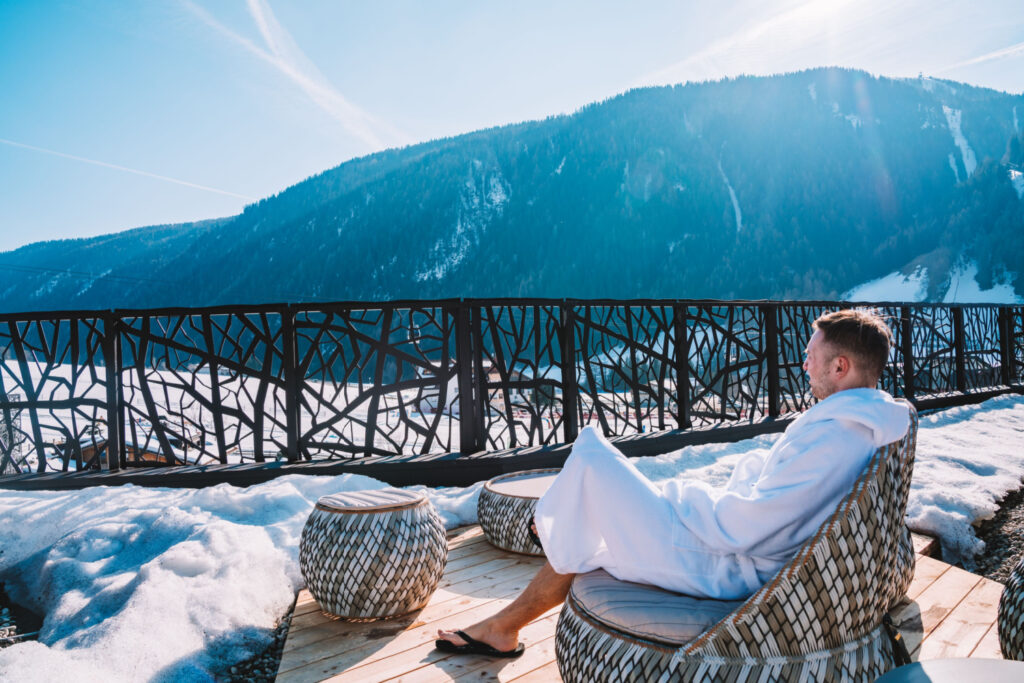 relaxed young man enjoying the mountain view from a luxury ski resort's open terrace
