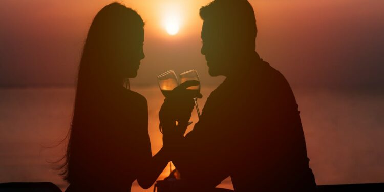 Silhouette of couple in love drinking wine during romantic dinner at sunset on the beach- Romantic Things to Do in Atlanta