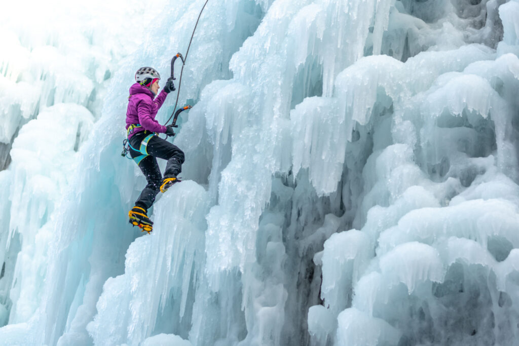woman conquering frozen heights with ice climbing and adventure sports equipment