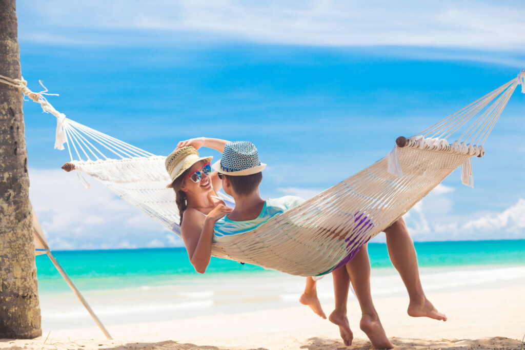 Young couple relaxing in a hammock by the beach of a Tulum resort