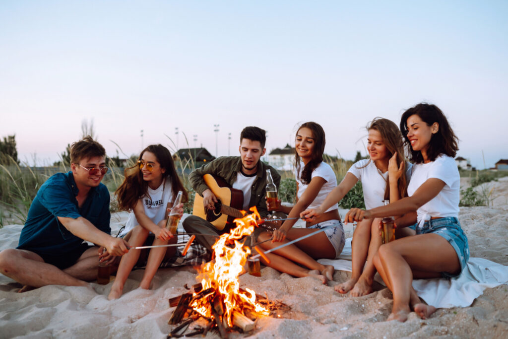 a group of joyful friends gathered around a campfire at the beach