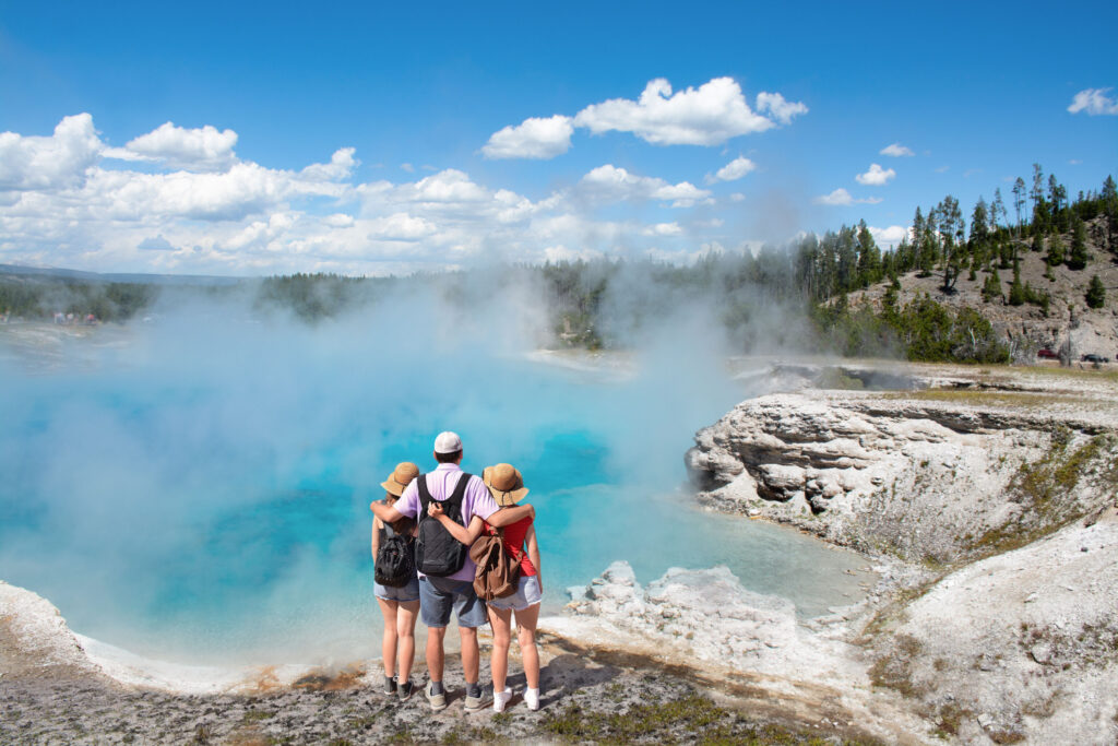 A family relishing the splendid sight of Excelsior Geyser Crater from the Midway Basin in Yellowstone National Park