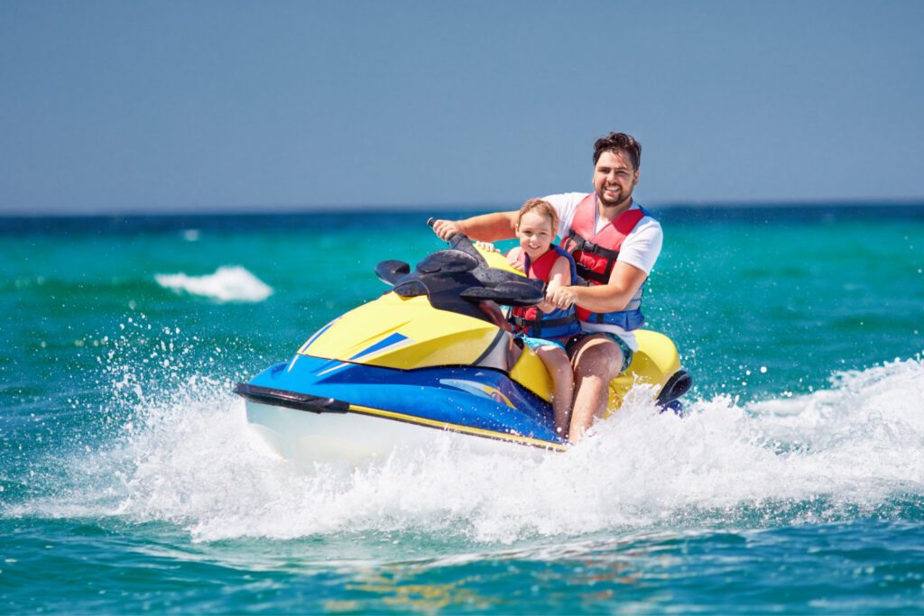 father and son having fun on jet ski at one of the isalnds in texas