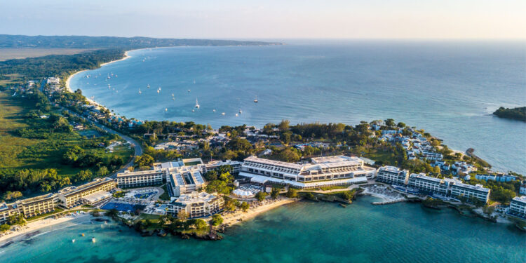 Aerial view of Negril, Jamaica, highlighting its beach, sunset, clear waters, and serene vacation allure