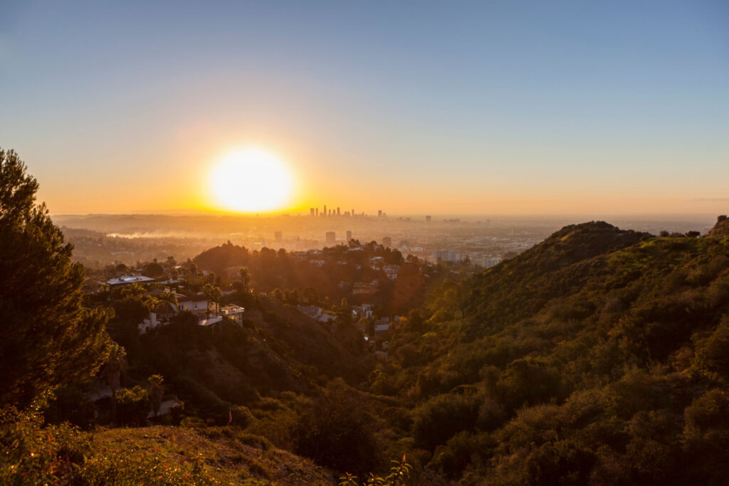 hazy orange sunrise scene from runyon canyon park, overlooking the cities in southern california
