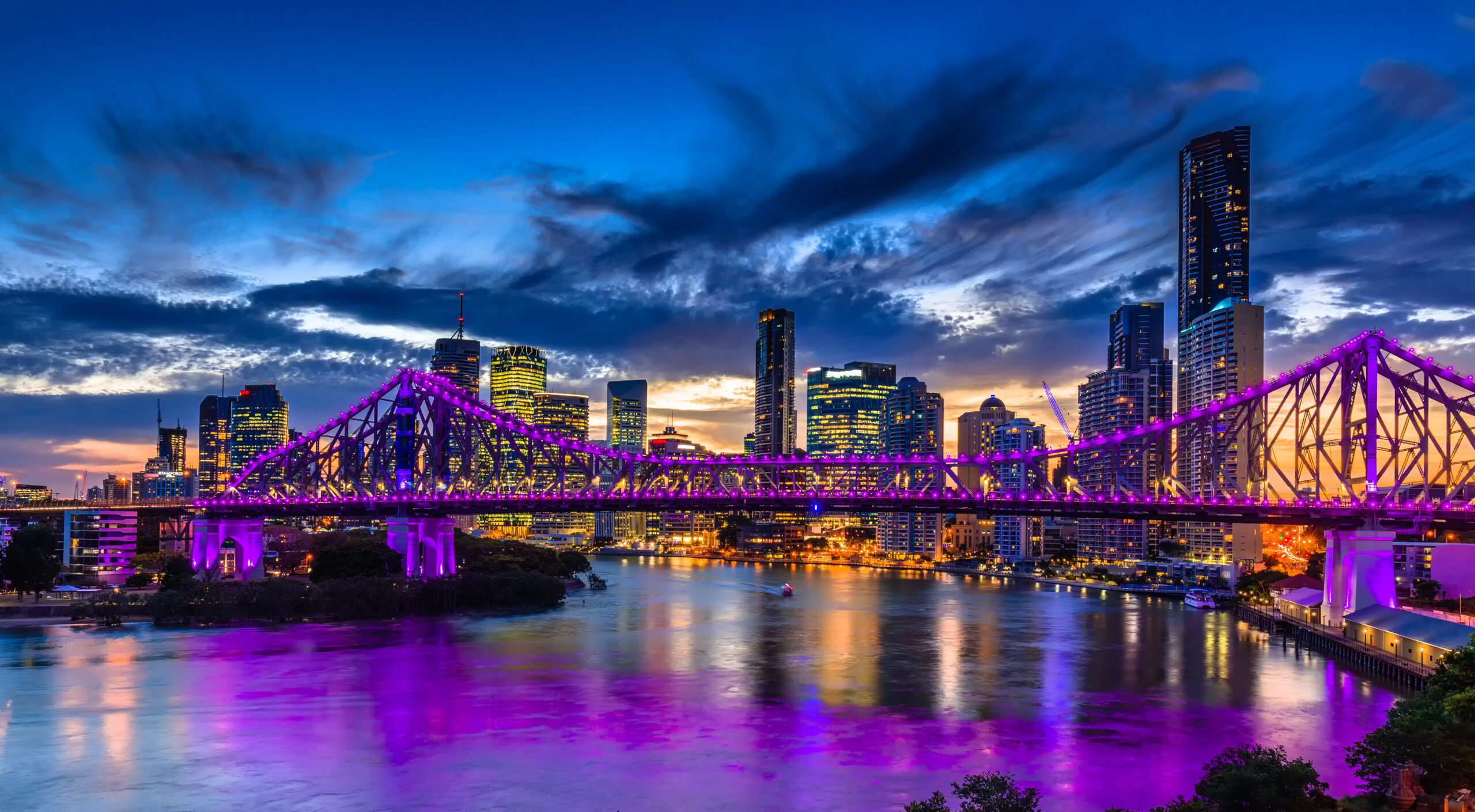 Vibrant night time panorama of Brisbane city with purple lights on Story Bridge, Australia